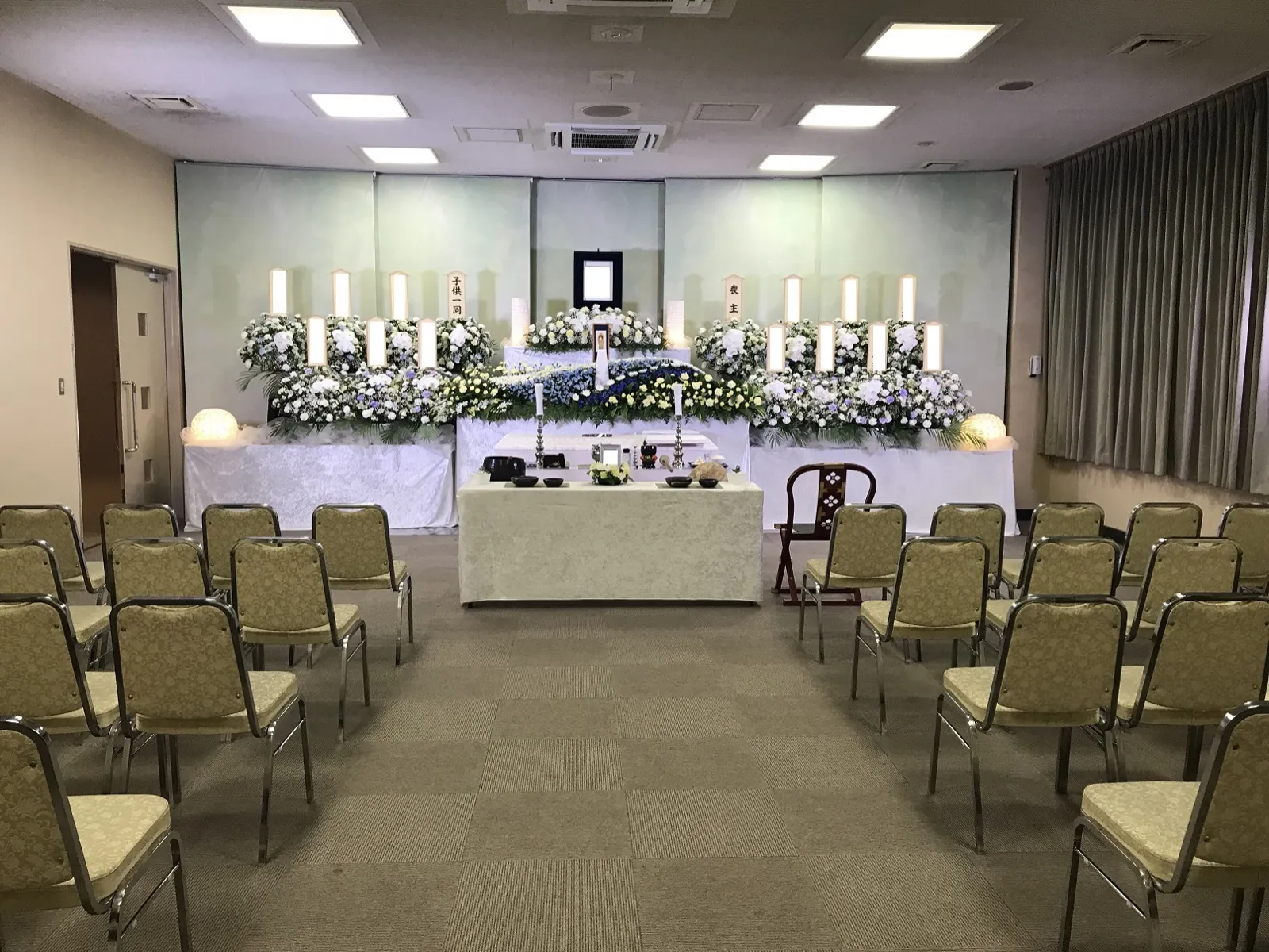 藤沢市斎場の式場。白い花の祭壇の前に、中央の通路をはさんで椅子が並ぶ